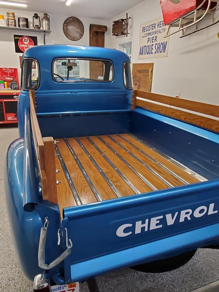 Blue vintage Chevrolet pickup truck with wooden bed displayed in a museum or showroom setting